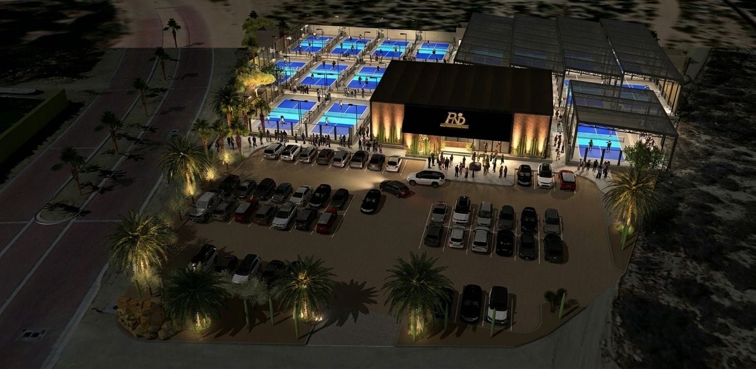 Night aerial of the full facility with the courts and clubhouse aglow